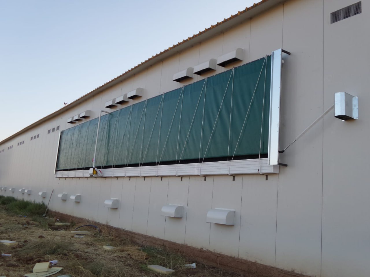 Evaporative cooling pad wall installed on a greenhouse facade in a hot, dusty climate
